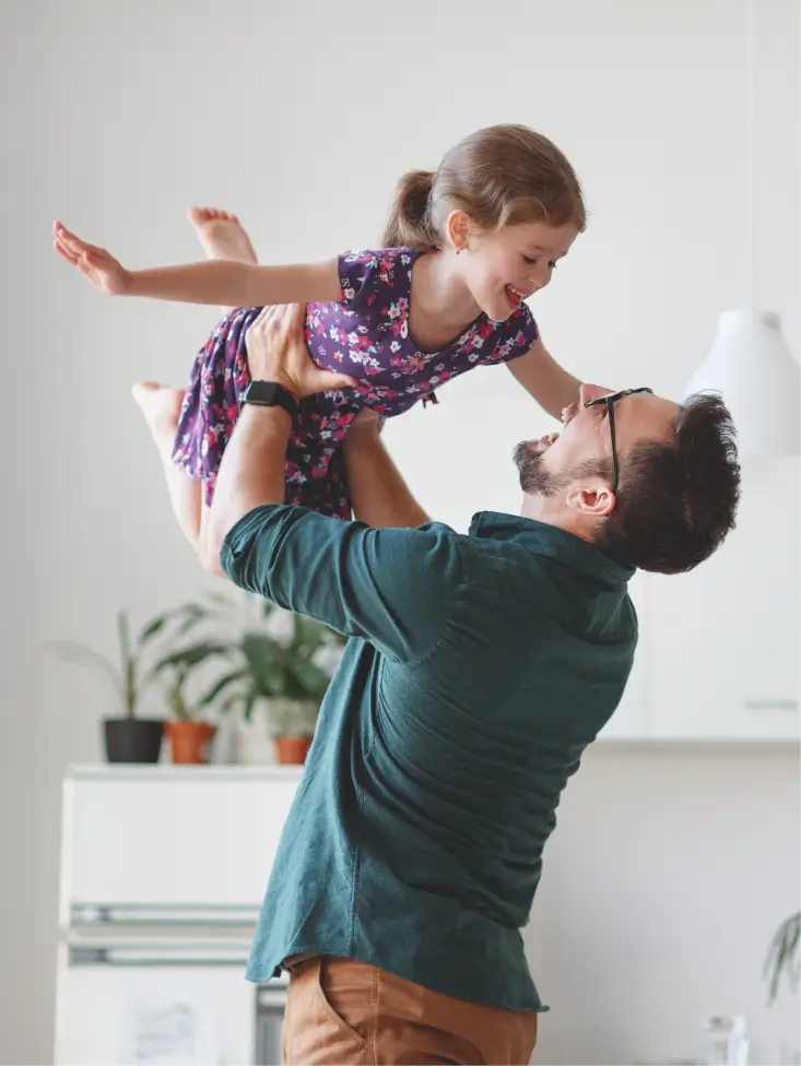 a man holding a little girl up in the air